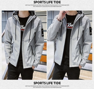 Close-up of light gray men's hooded jacket featuring a zippered pocket and arm badge