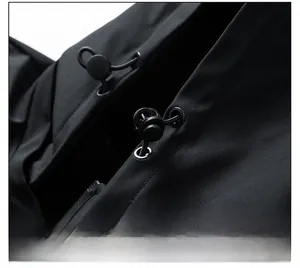 Macro view of adjustable drawstring cord lock on black waterproof outdoor jacket hood