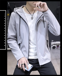 Detail view of light grey hooded windbreaker jacket with functional pockets and drawstring
