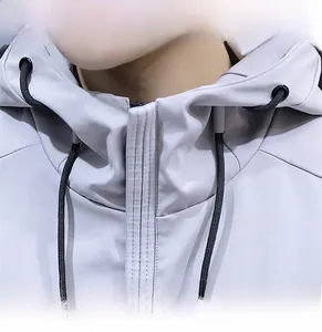 Close-up of a light grey hooded jacket featuring a textured fabric and black drawstrings