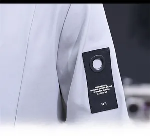Detail of light gray jacket sleeve featuring black patch with silver metal eyelets and text