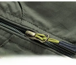 Detail of army green fishing vest with smooth metal zipper and woven puller texture