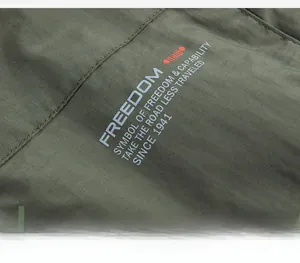 Detail of army green outdoor vest fabric with white freedom text and red icon