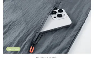 Detail view of the gray sun protection jacket showing a zippered pocket with orange puller