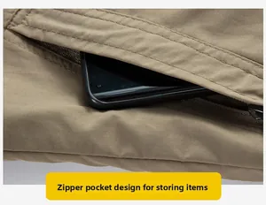 Detail of khaki outdoor jacket zipper pocket showing storage capacity for a phone
