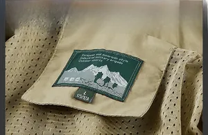 Detail of khaki outdoor jacket showing breathable mesh lining and size label on the collar