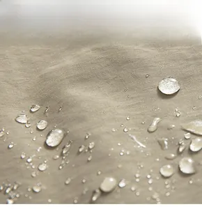 Macro view of khaki outdoor fabric showing high-tech waterproof coating and water droplets