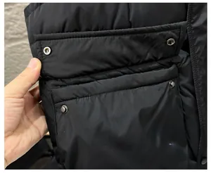 Détail de la poche à rabat de veste cargo avec bouton pression argenté et tissu noir mat