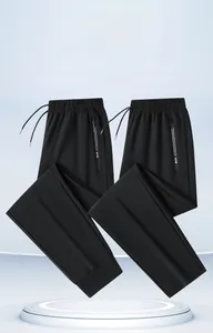 Detail of black sports trousers featuring zipper pockets with NEW text and drawstring waist