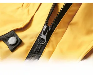 Detail shot of the smooth resin zipper and snap button on a yellow outdoor jacket