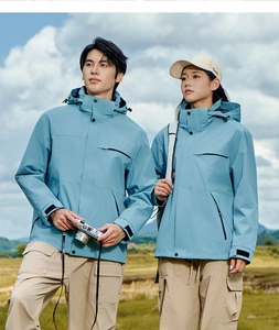 Couples in blue waterproof jackets and khaki pants posing in a grassy mountain field