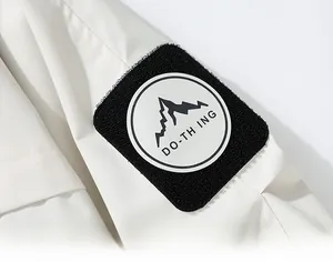 Detailed close-up of a white jacket sleeve featuring a black mountain logo arm patch