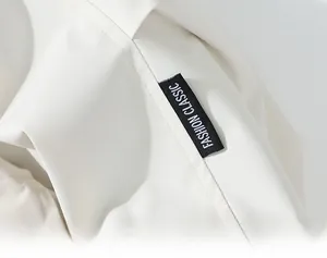 Detail shot of white jacket sleeve featuring black Fashion Classic woven label and stitching