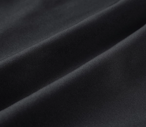 Detail of black moisture-wicking quick-dry fabric showing fine twill texture and sheen