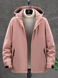 Pink waterproof outdoor jacket with hood and Explore text on a grey textured wall