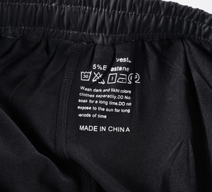 Detailed macro view of elastic waistband and printed care label on black sports pants