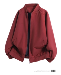 Macro shot of dark red bomber jacket showing ribbed cuffs and zipper pockets on white