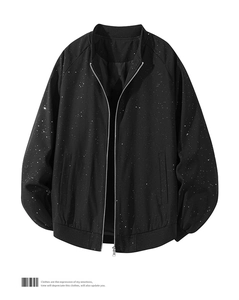 Detail of black bomber jacket with white star splatter pattern and ribbed cuffs