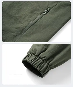 Close-up detail of army green outdoor jacket featuring zipper pockets and elastic cuffs