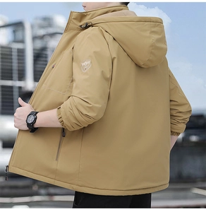 Close-up of khaki outdoor jacket sleeve featuring detailed shield embroidery and elastic cuff