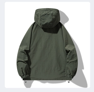 Detail view of olive green hooded jacket showing windproof fabric texture and hem drawstrings