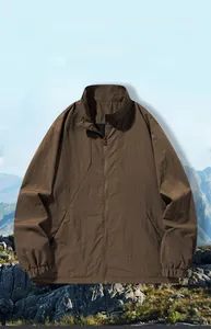 Dettaglio giacca outdoor marrone scuro in tessuto antivento su sfondo di montagna