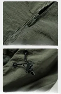Detail of dark olive outdoor jacket showing metal zipper and adjustable drawstring hood