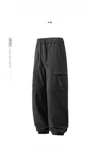Detail of black cargo pants featuring elastic drawstring waist and side flap pockets