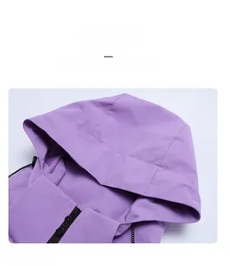 Detail of a purple waterproof jacket featuring a detachable hood and high collar zipper