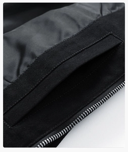 Detailed close-up of a high-quality silver metal zipper and reinforced pocket on a black jacket
