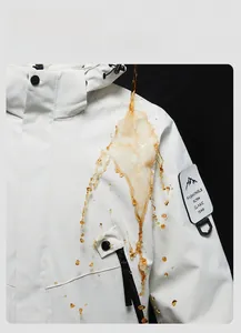 Close-up of white waterproof jacket showing liquid repelling on stain-resistant fabric