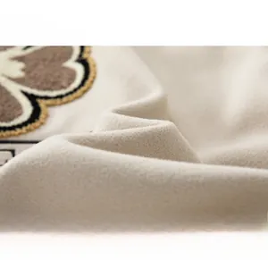 Dettaglio macro della salopette retrò beige con tessuto strutturato e ricamo floreale