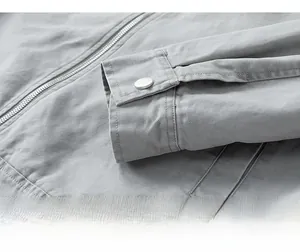 Detail of grey utility jacket cuff with metal button and textured canvas fabric grain