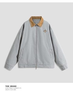 Detail of contrast corduroy collar and brand logo patch on gray workwear jacket
