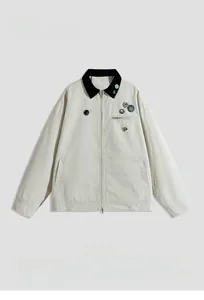 Detailed view of beige jacket with black corduroy collar and colorful metal badges