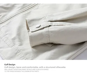 Detail of off-white work jacket showing twill fabric texture and metal button on cuff