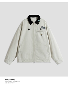 Detail of light beige workwear jacket with embroidered badges and contrast collar