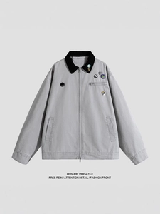 Light gray casual jacket with black collar and vibrant cartoon badges in a flat lay view