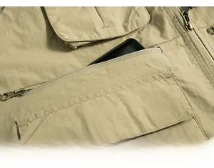 Detail of khaki outdoor vest showing a secure metal zipper pocket with a phone inside