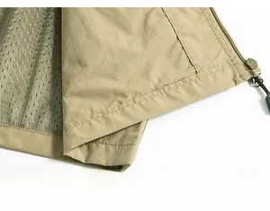 Detail of khaki outdoor vest hem with durable stitching, mesh lining and zipper pocket