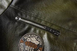 Makrodetail der olivgrünen Lederjacke mit Stickerei-Patch und Metallreißverschluss