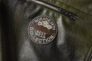Detail der armeegrünen PU-Lederjacke mit Motorrad-Stickerei und robustem Metall-Reißverschluss