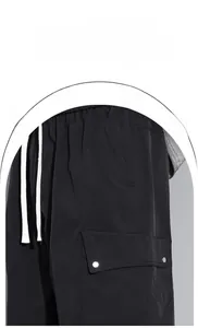 Detail der schwarzen Cargohose mit weißen Kordelzügen und großen Seitentaschen mit Nieten