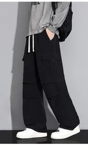 Detail view of black cargo pants with multiple pockets and white contrast drawstrings