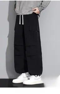 Detail of loose fit black cargo pants featuring white drawstring and multi-pocket design
