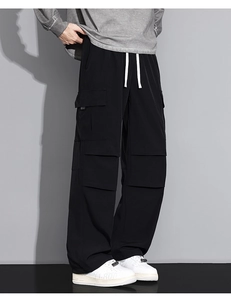 Detail shot of black cargo pants featuring white drawstring waist and large side utility pockets