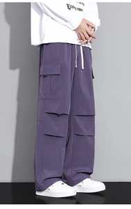 Detail of dark purple cargo pants featuring large 3D side pockets and white drawstring