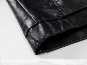 Close-up detail of the black leather jacket hem showing smooth texture and metal zipper