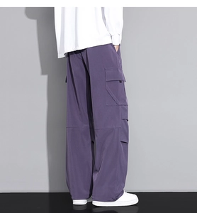 Detail view of baggy dark purple cargo pants featuring large side flap pockets on the leg
