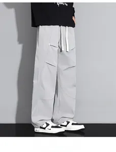 Détail du pantalon large gris clair avec coutures diagonales et cordon de serrage blanc